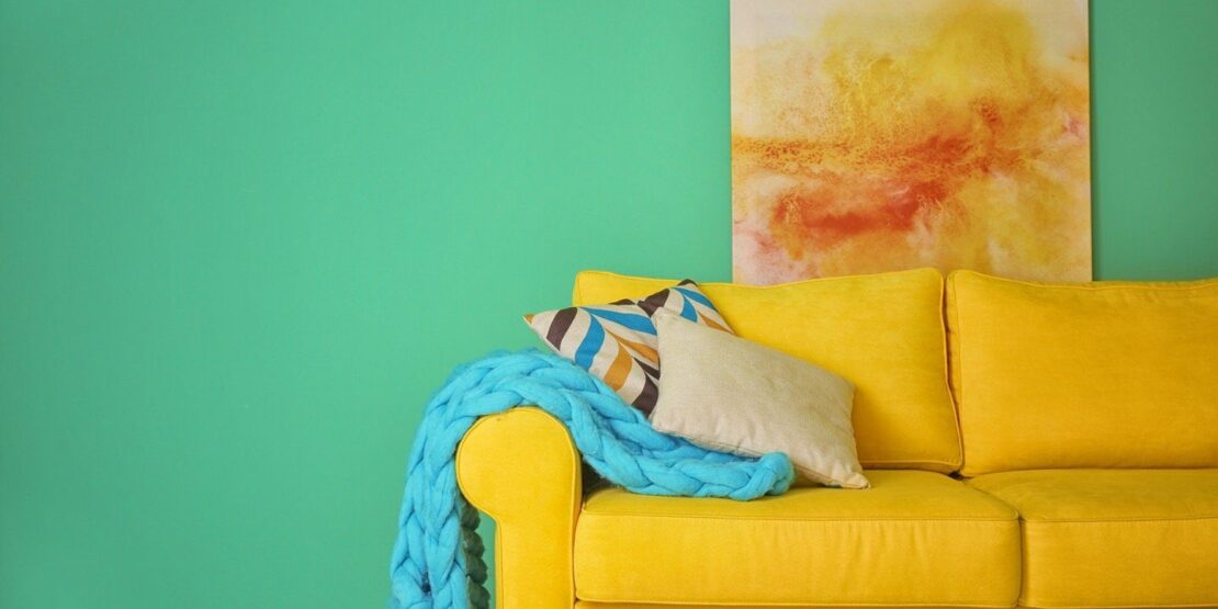 Gelbe Couch vor einer grünen Wand fällt auf, aber wirkt stimmig.
